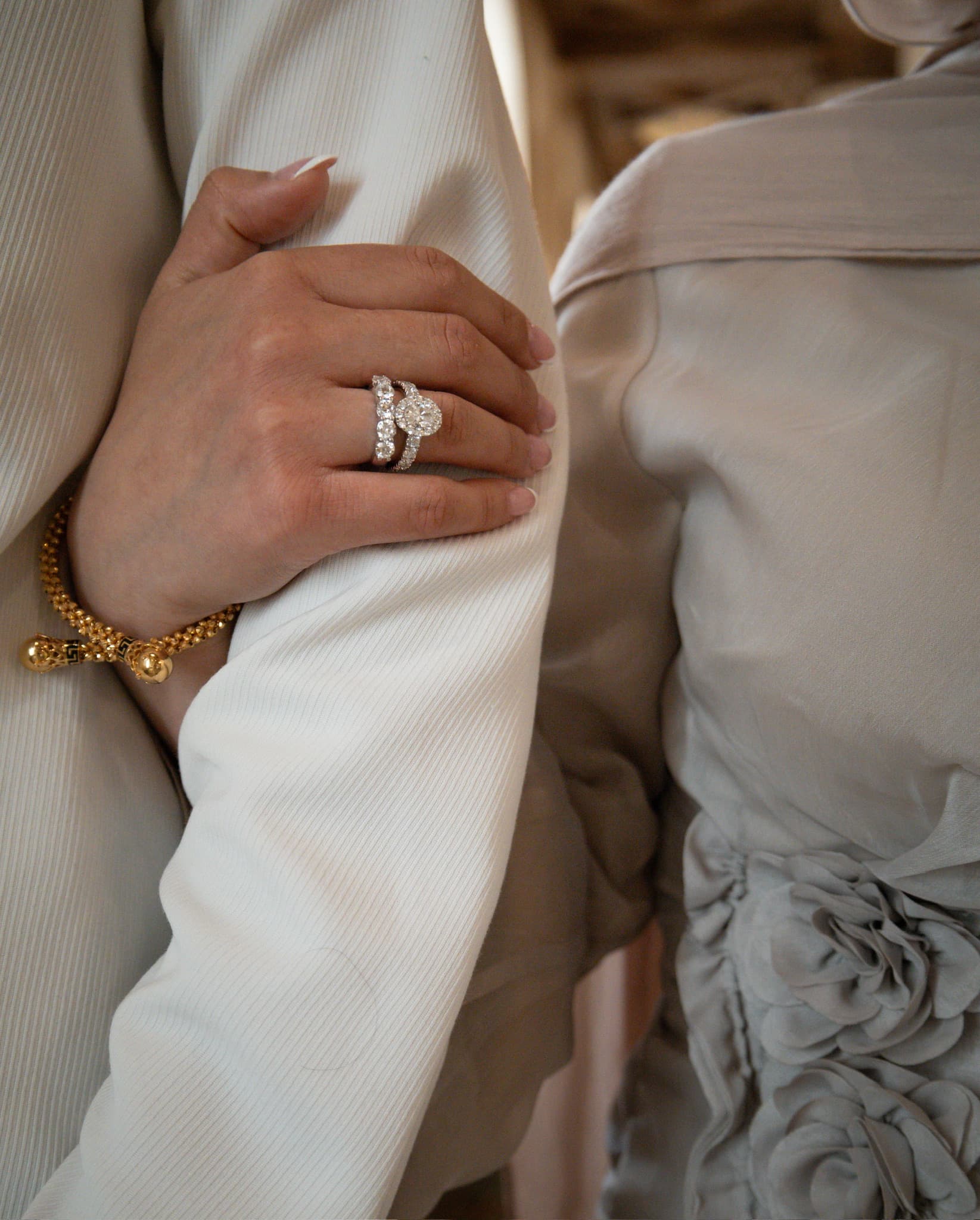Close-up of an engagement ring as the couple's arms embrace, photographed by ShuhraBilNoor